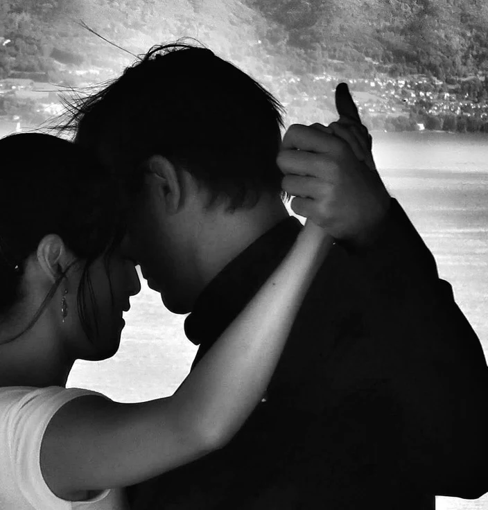 Archival silhouette of Shawn dancing before a lake, with only the edge of his partner’s profile and her arm visible