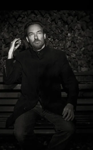 Undated black-and-white archival portrait of Shawn Koppenhoefer seated and looking at the camera
