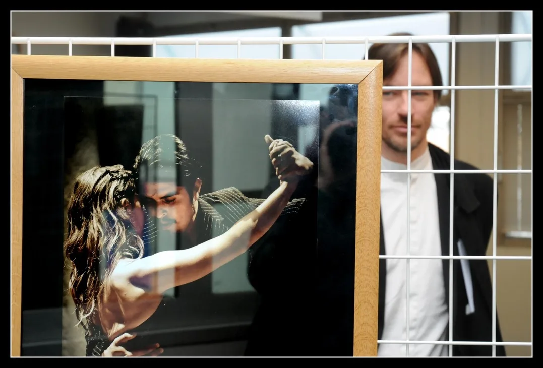 A framed tango photograph in the foreground with Shawn Koppenhoefer behind it during his exhibition in Décines