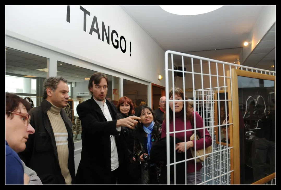 Shawn Koppenhoefer presents an exhibition of his tango photographs to a group of visitors in Décines